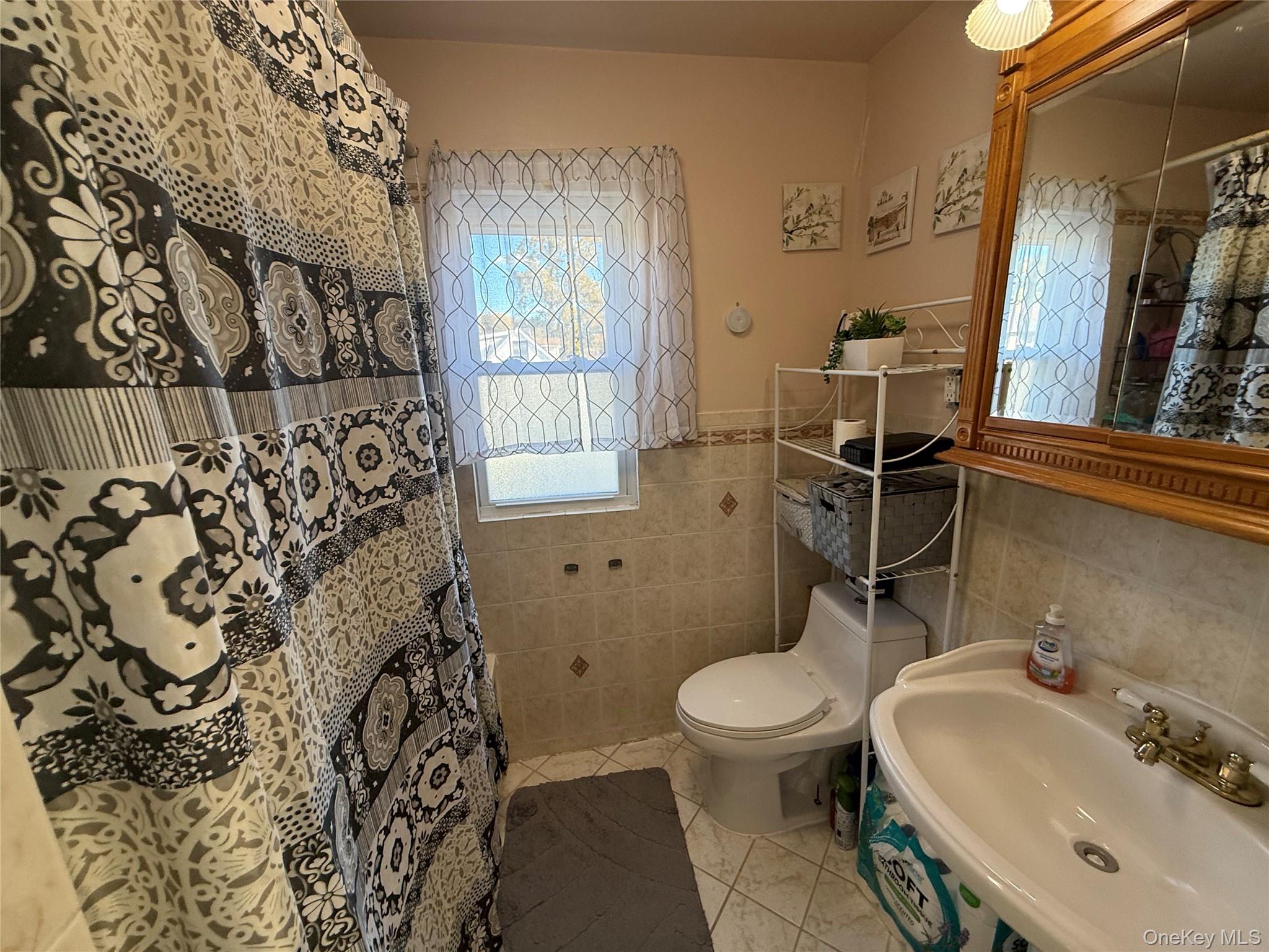 136-29 220th Place Queens, NY 11413 - Photo 42 of 45 Bathroom with tile walls, a shower with curtain, and light tile patterned floors