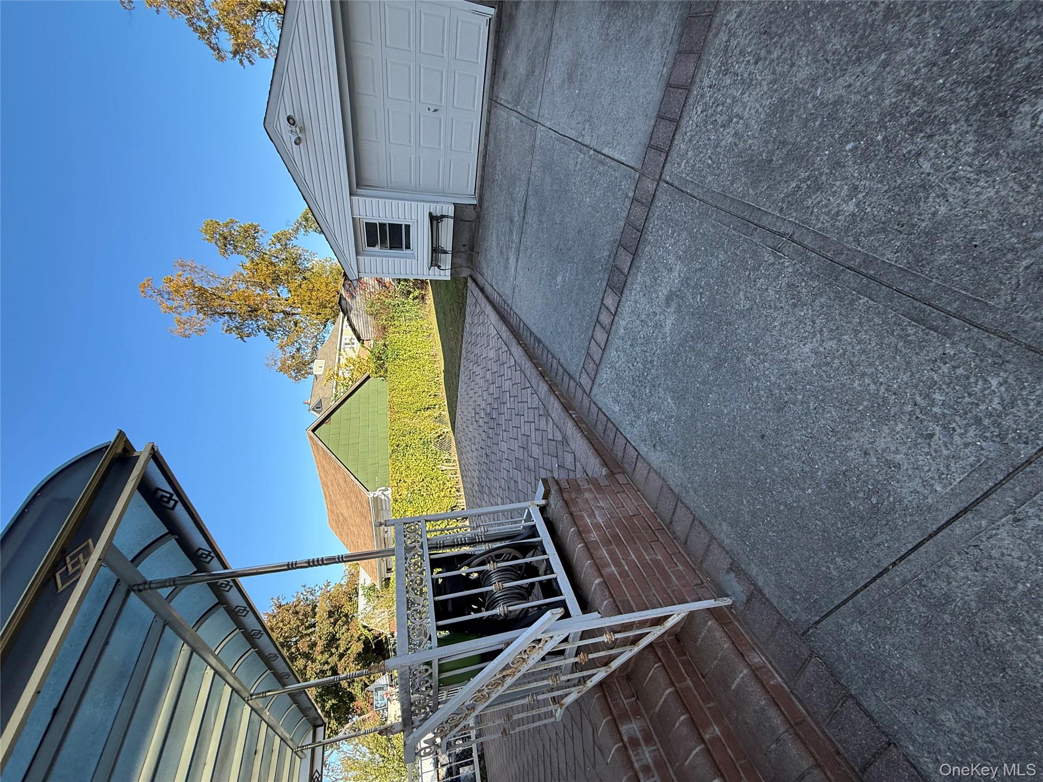 136-29 220th Place Queens, NY 11413 - Photo 8 of 45 View of yard featuring driveway, a detached garage, a patio area, and an outbuilding
