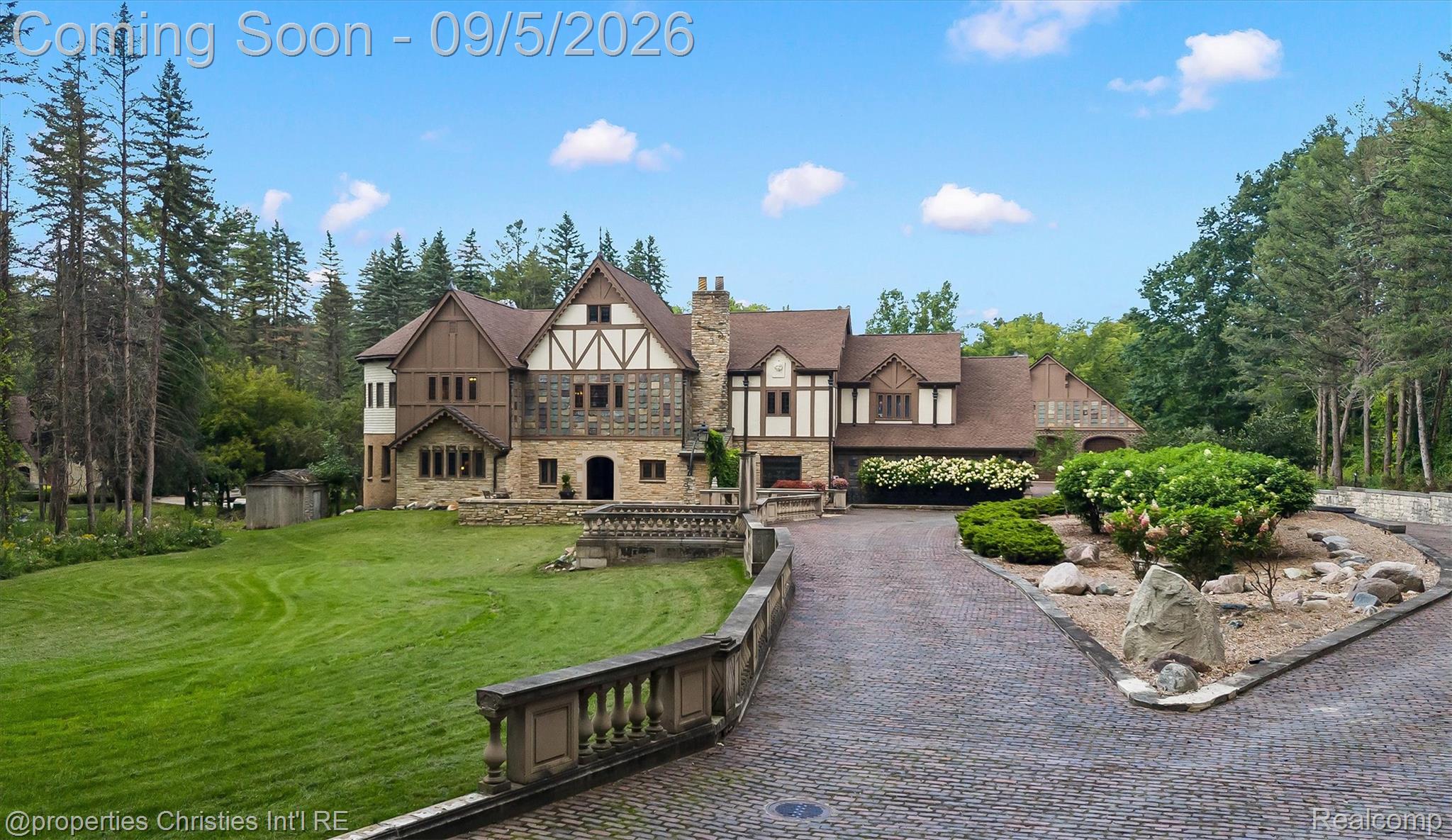 1540 Mill Race Road Rochester, MI 48306 - Photo 93 of 99 Tudor-style exterior with stone and timber accents, a paver driveway, lush landscaping, and a terraced stone balustrade