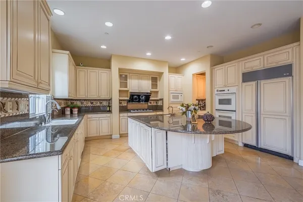 a large kitchen with kitchen island granite countertop a sink counter space appliances and a large window