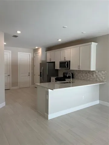 a large kitchen with stainless steel appliances granite countertop a large counter top and a stove with wooden floor