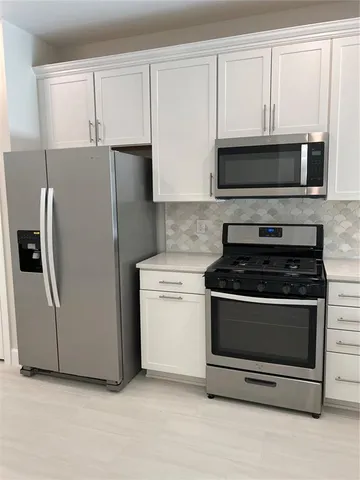 a kitchen with stainless steel appliances white cabinets a stove a microwave and a refrigerator