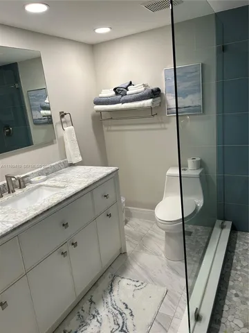 a bathroom with a granite countertop sink a toilet and a mirror