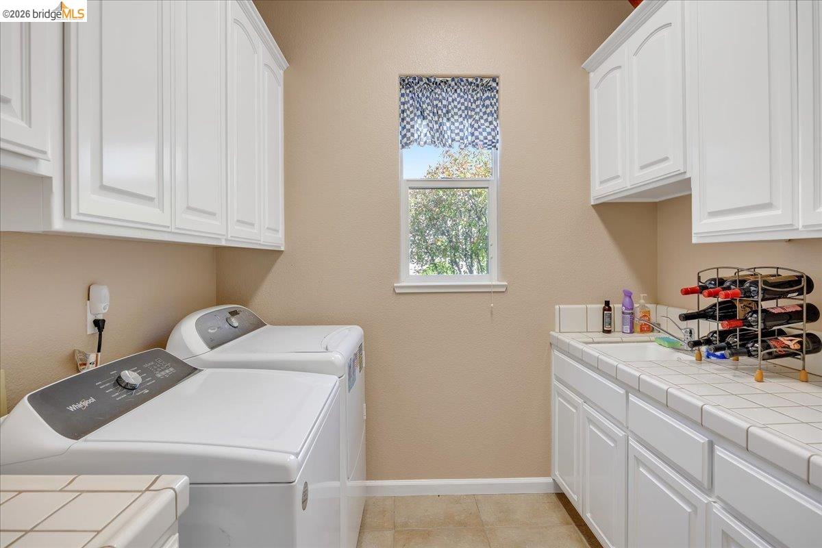 158 Rock Ridge Lane Copperopolis, CA 95228 - Photo 27 of 72 Laundry room with extensive white cabinetry, a built-in sink, and tile countertops