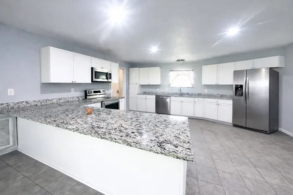 a large kitchen with kitchen island a large counter top stainless steel appliances and cabinets