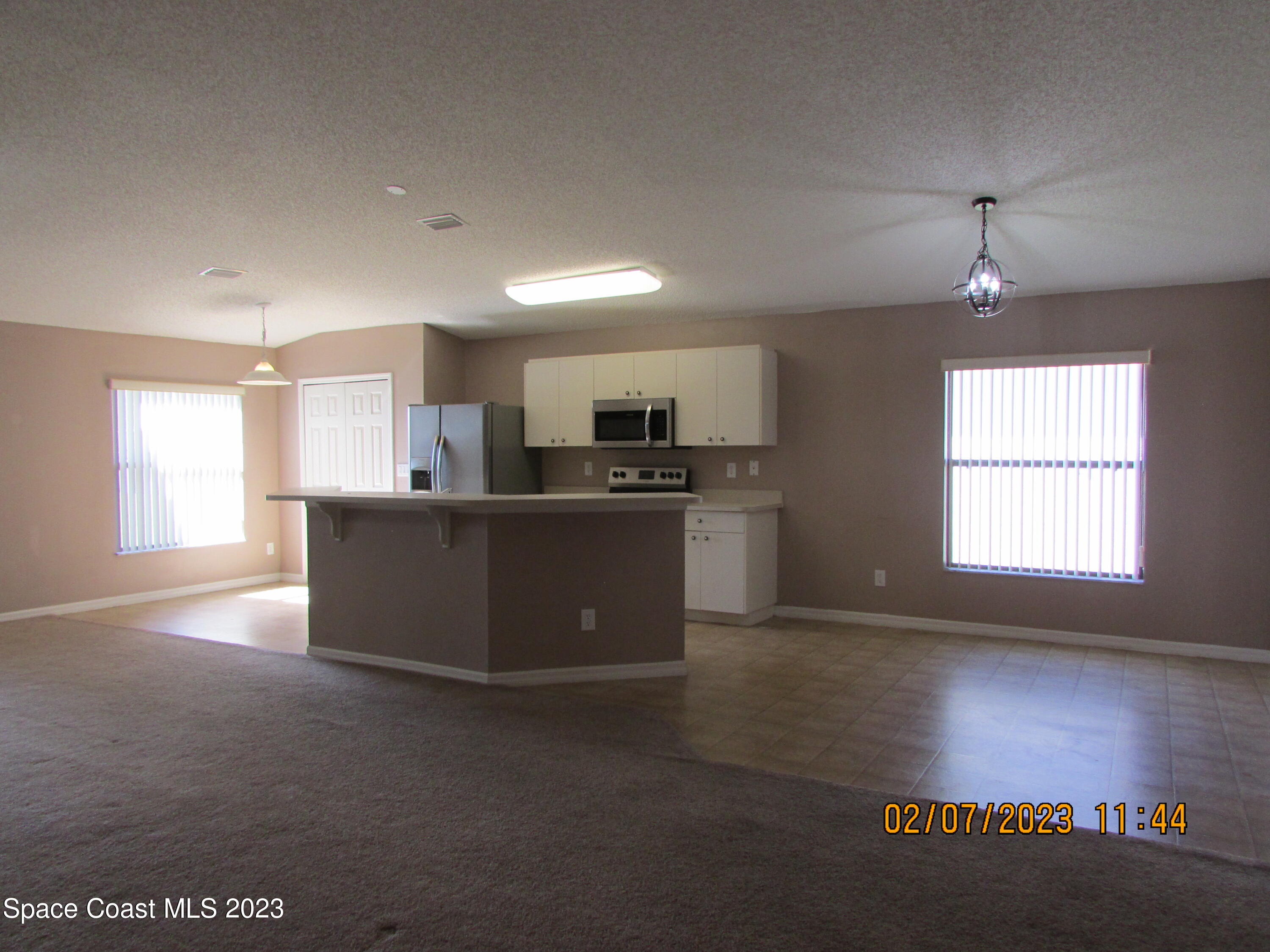 4001 Wilkes Drive Melbourne, FL 32901 - Photo 11 of 21 a kitchen with stainless steel appliances granite countertop a stove top oven a sink dishwasher a refrigerator and a dining table with wooden floor