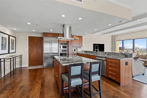 a kitchen with stainless steel appliances granite countertop a kitchen island hardwood floor sink stove dining table and chairs