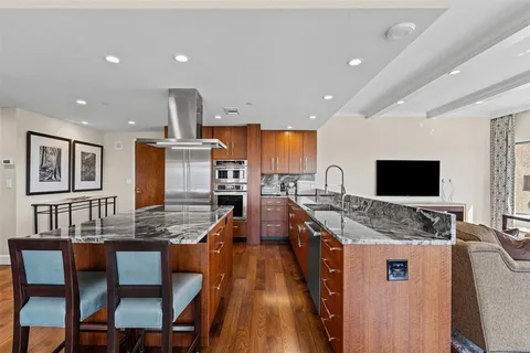 a kitchen with stainless steel appliances granite countertop a stove top oven a sink a dining table and chairs