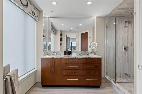 a bathroom with a granite countertop sink a mirror and shower