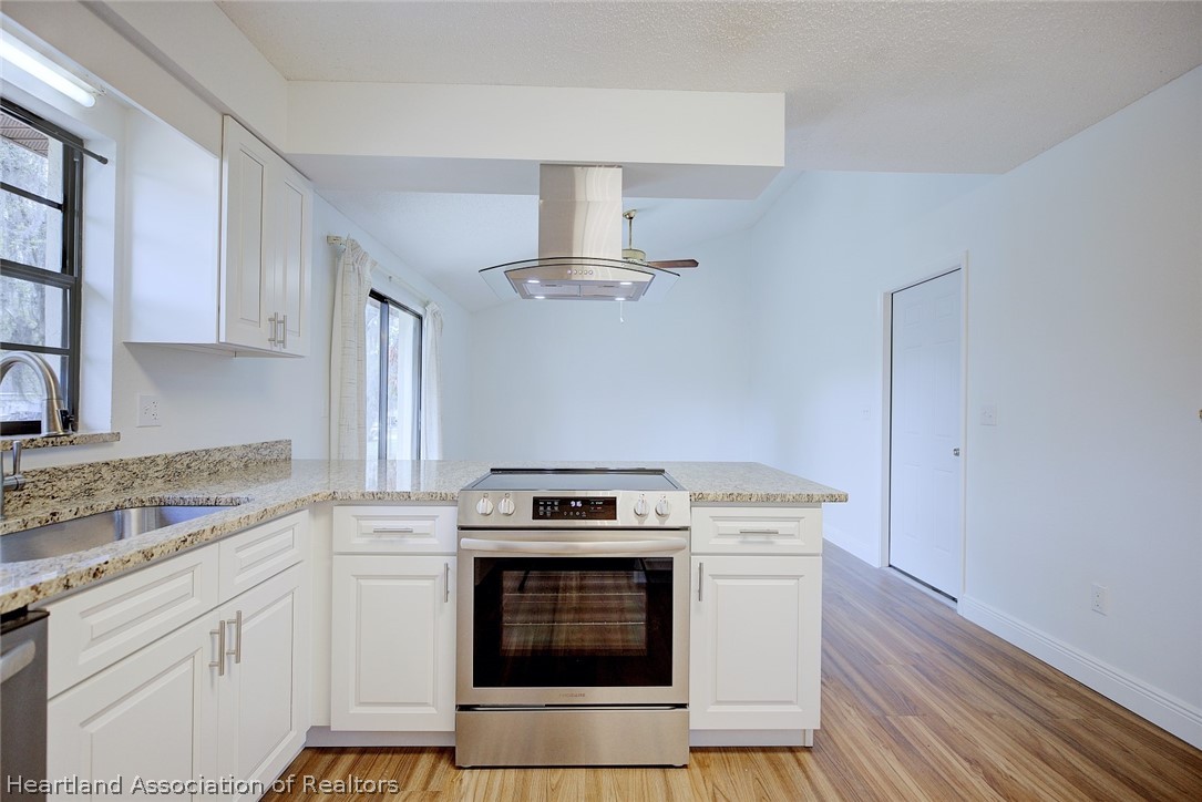 2052 West Stryker Road Avon Park, FL 33825 - Photo 17 of 45 a kitchen with a stove and white cabinets