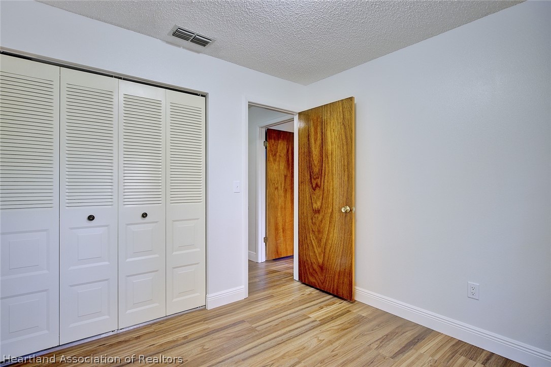 2052 West Stryker Road Avon Park, FL 33825 - Photo 34 of 45 an empty room with wooden floor and closet area