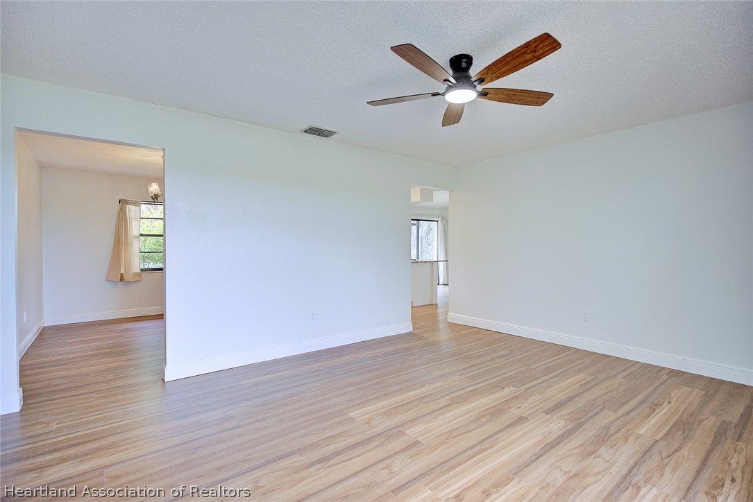 2052 West Stryker Road Avon Park, FL 33825 - Photo 7 of 45 an empty room with wooden floor a ceiling fan and windows
