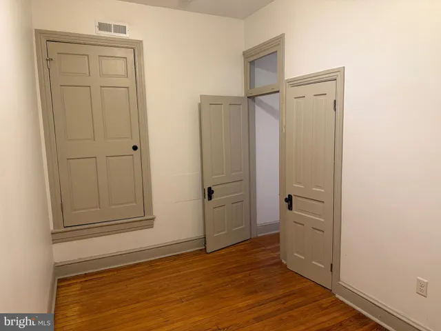 an empty room with wooden floor and closet area
