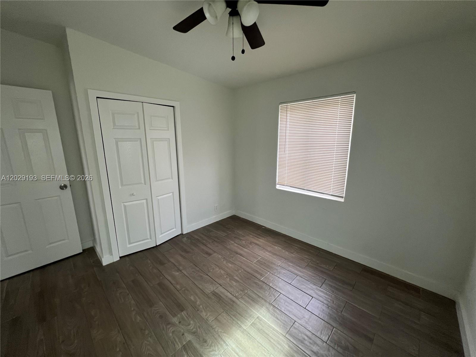 2240 Rutland Street Opa-Locka, FL 33054 - Photo 6 of 11 an empty room with wooden floor cabinet and windows