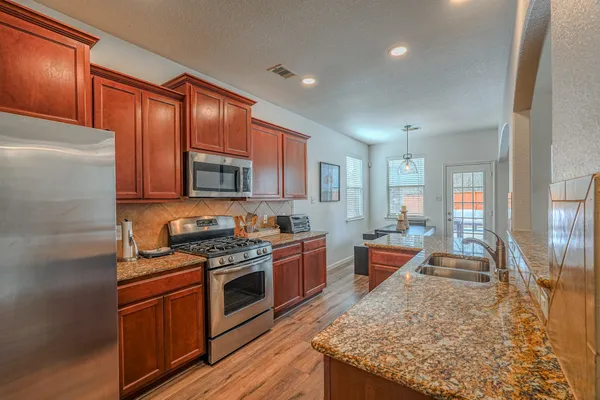 a large kitchen with stainless steel appliances granite countertop a stove a sink dishwasher and a refrigerator