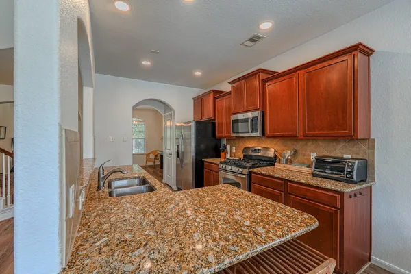 a kitchen with stainless steel appliances granite countertop a stove top oven a sink dishwasher and cabinets with wooden floor