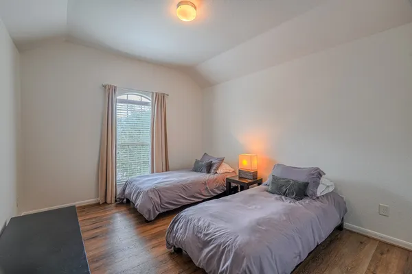a bedroom with two beds and wooden floor
