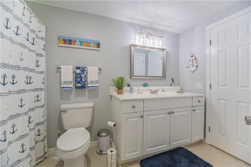 4 Chateau Way Naples, FL 34112 - Photo 15 of 21 a bathroom with a granite countertop toilet a sink and a mirror