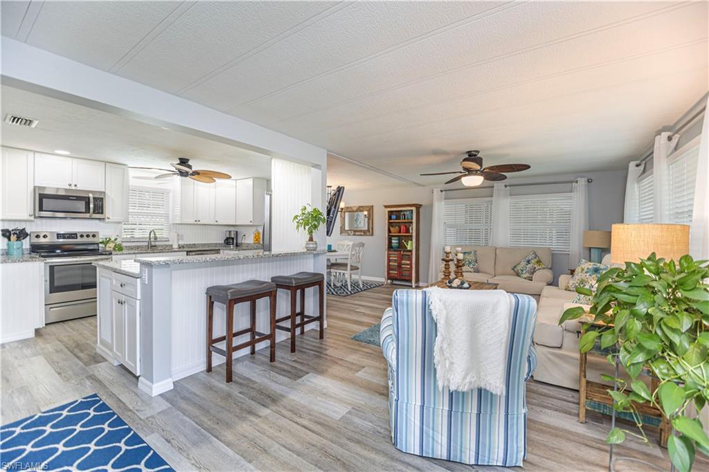 4 Chateau Way Naples, FL 34112 - Photo 4 of 21 a kitchen with stainless steel appliances granite countertop a stove top oven a sink a dining table and chairs with wooden floor