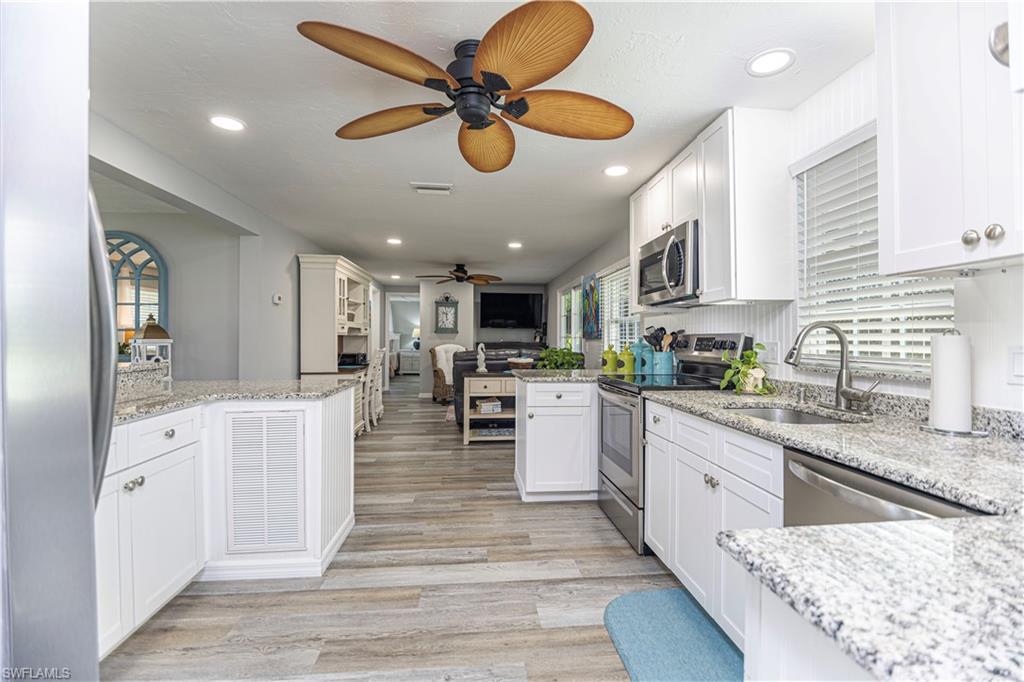 4 Chateau Way Naples, FL 34112 - Photo 5 of 21 a kitchen with stainless steel appliances granite countertop hardwood floor sink stove dining table and chairs