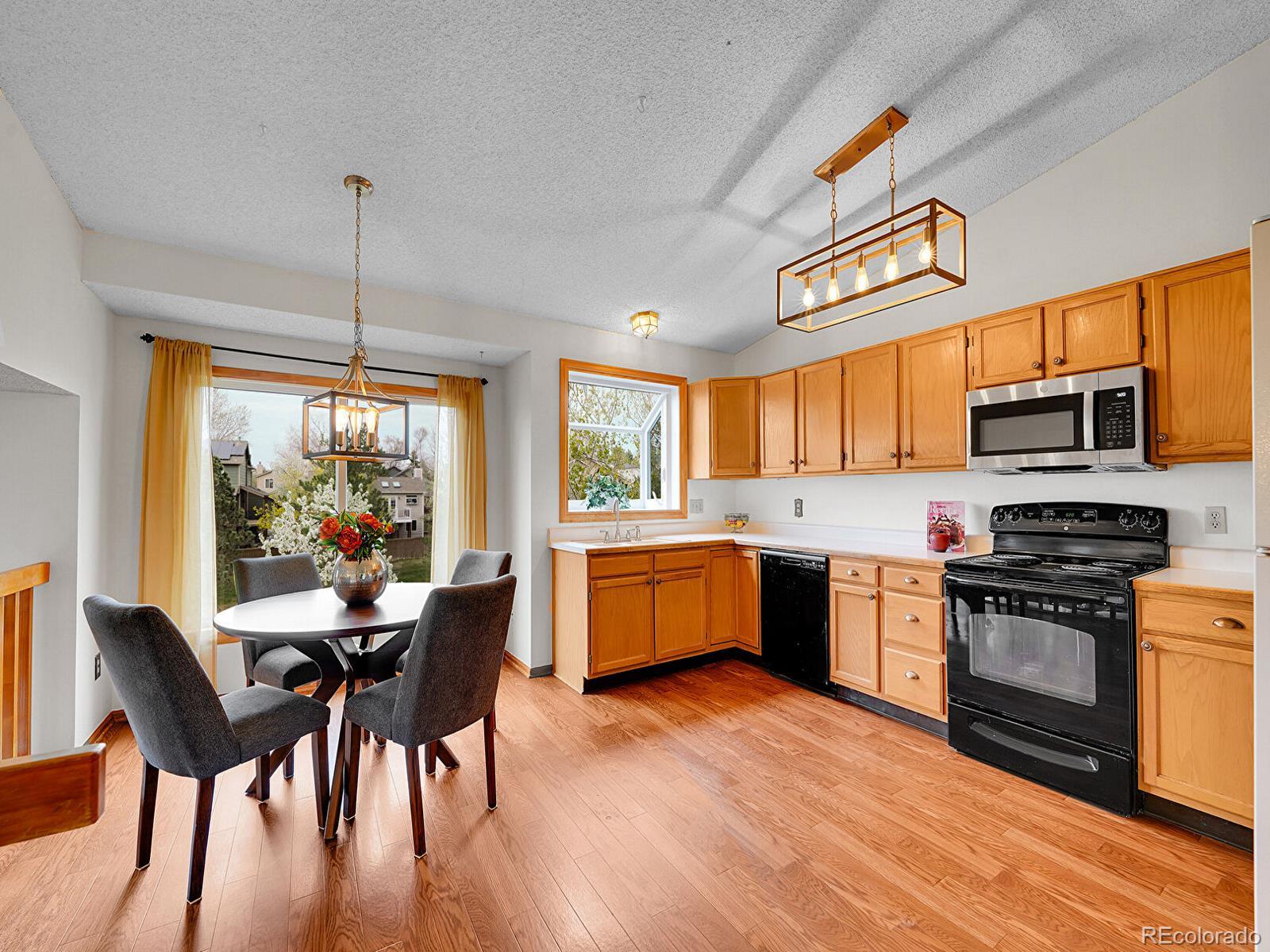 6343 Laguna Circle Highlands Ranch, CO 80130 - Photo 6 of 43 a kitchen with stainless steel appliances granite countertop wooden floors stove top oven with a dining table and chairs