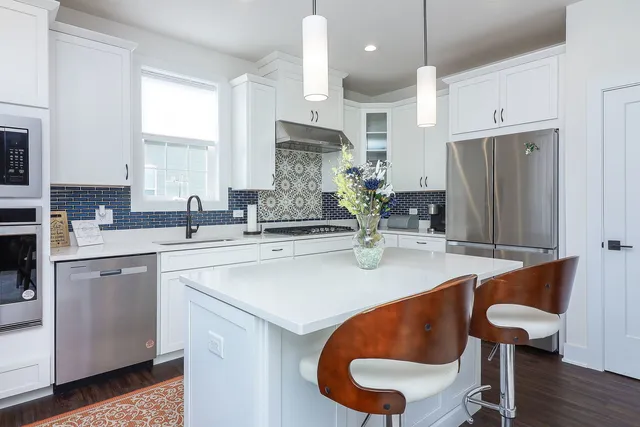 a kitchen with stainless steel appliances granite countertop a sink a stove a refrigerator and island with wooden floor