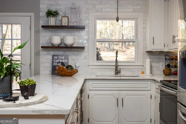 a kitchen with stainless steel appliances a white sink a window and white cabinets