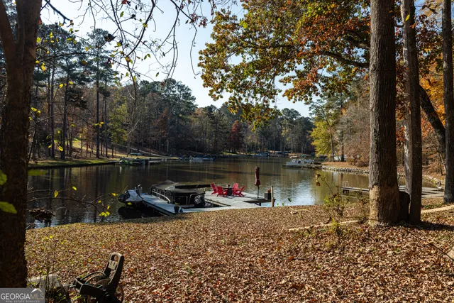a lake view with a bench under large trees