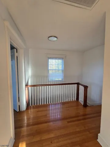 a view of hallway with wooden floor and a window