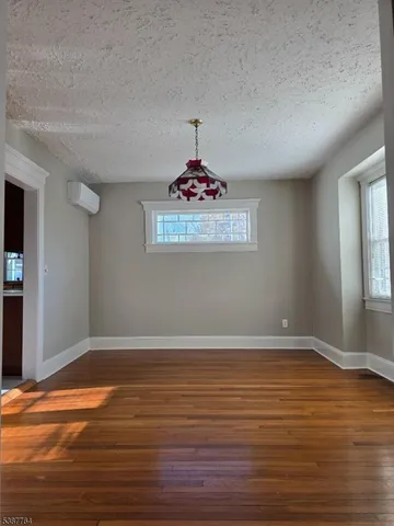 an empty room with wooden floor chandelier and window