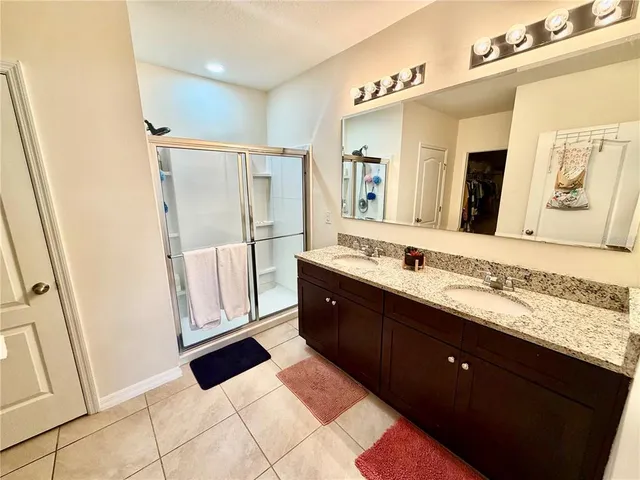 a spacious bathroom with a double vanity sink a mirror and a shower