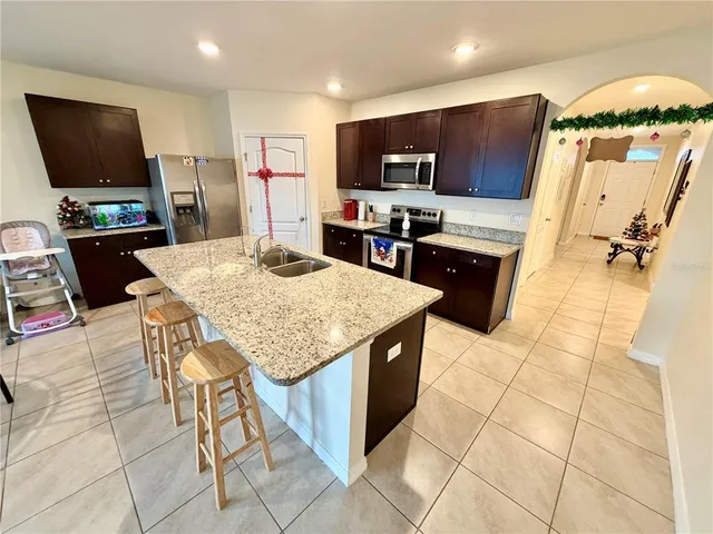 a kitchen with stainless steel appliances kitchen island granite countertop a sink and a stove top oven with wooden floor