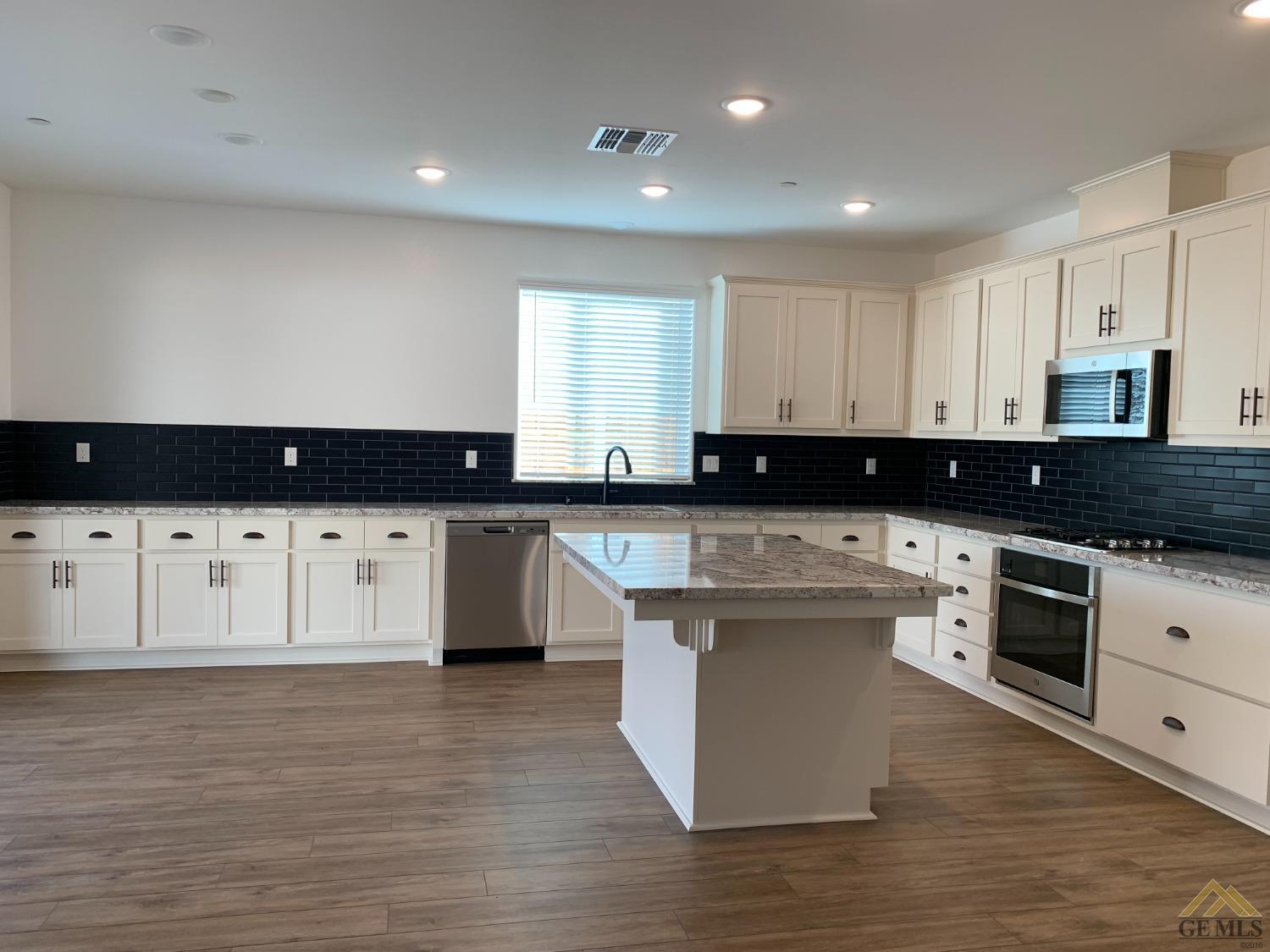 Undisclosed Address Bakersfield, CA 93314 - Photo 3 of 8 a large kitchen with granite countertop a stove top oven a sink and white cabinets