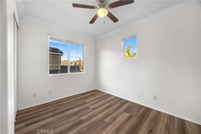 a view of an empty room with window and chandelier fan