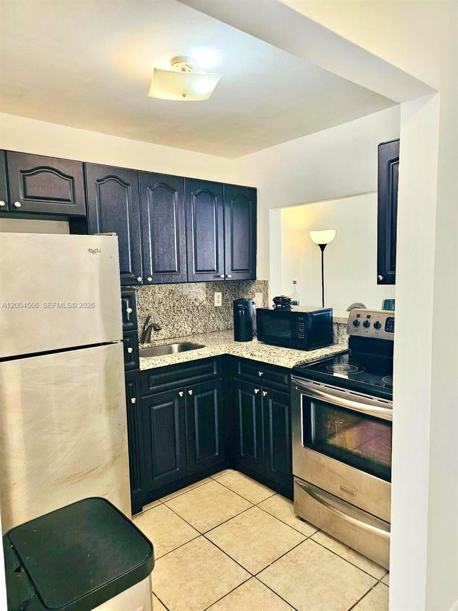 1441 Lincoln Road, Unit 212 Miami Beach, FL 33139 - Photo 6 of 9 a kitchen with a sink a stove and a refrigerator