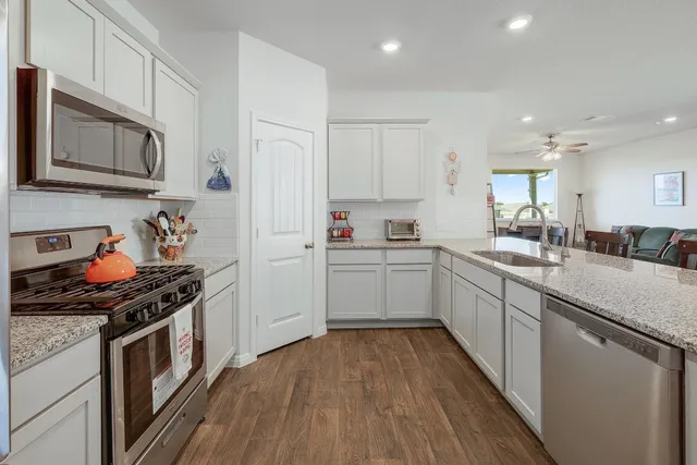 a kitchen with stainless steel appliances a white stove top oven sink and cabinets