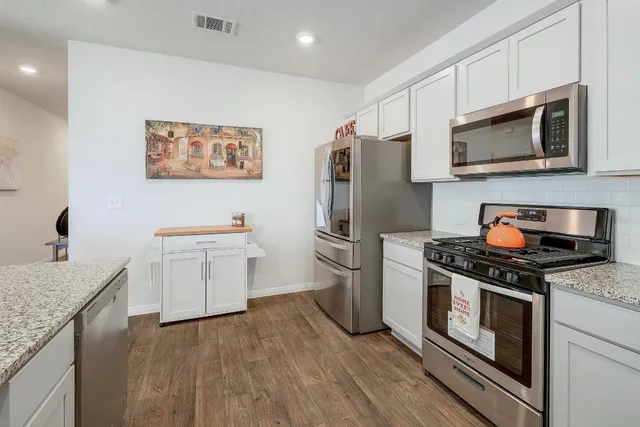 a kitchen with stainless steel appliances a stove microwave and a refrigerator