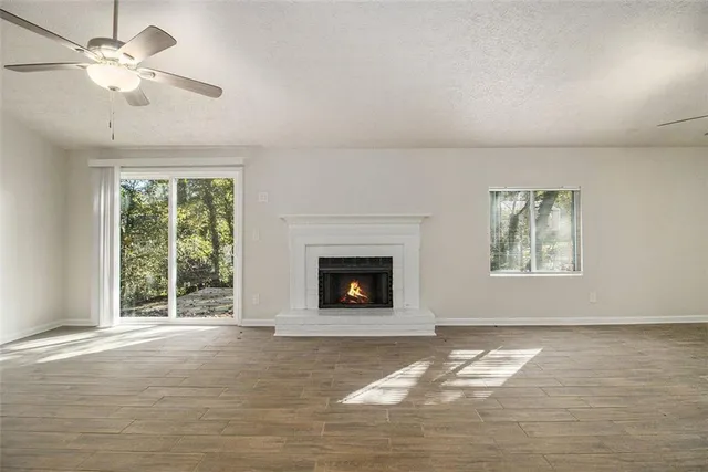 a view of a livingroom with a fireplace a ceiling fan and windows
