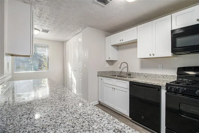 a kitchen with granite countertop a sink stainless steel appliances and cabinets