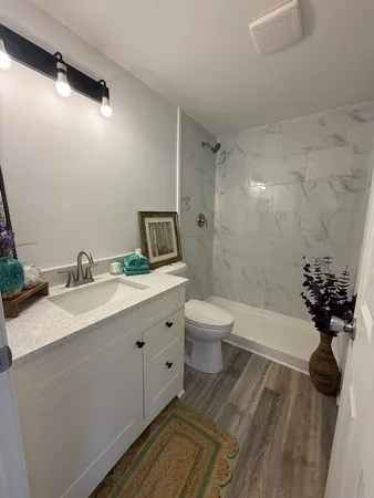 a spacious bathroom with a granite countertop sink a toilet and a bathtub