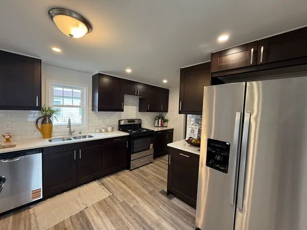 a kitchen with stainless steel appliances granite countertop a refrigerator a sink a stove a microwave and wooden floor