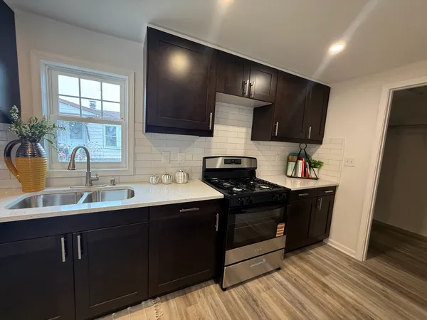 a kitchen with stainless steel appliances a sink dishwasher a refrigerator and a stove with wooden floor