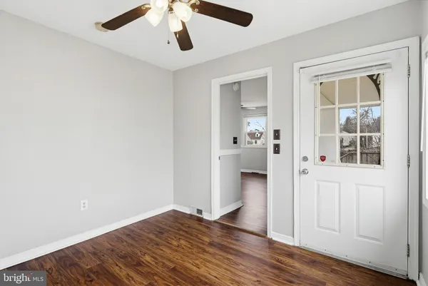 an empty room with wooden floor and ceiling fan
