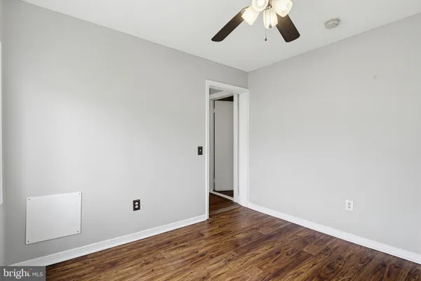 an empty room with wooden floor chandelier fan and windows