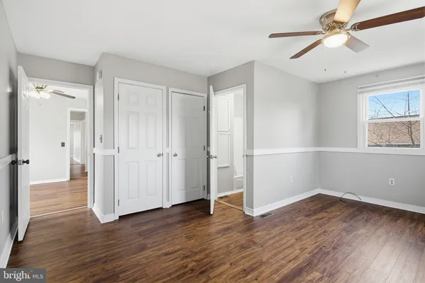 an empty room with wooden floor closet and ceiling fan