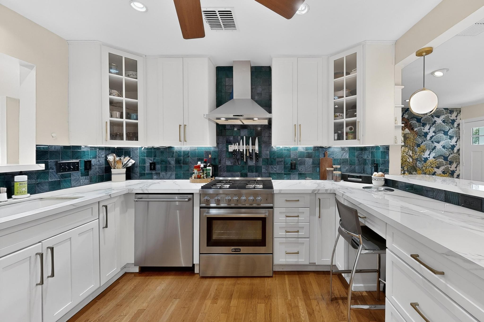 1906 Collier Street Austin, TX 78704 - Photo 3 of 40 Kitchen view of white cabinets, decorative backsplash, gas stove, light colored porcelain countertops, and glass insert cabinets.
