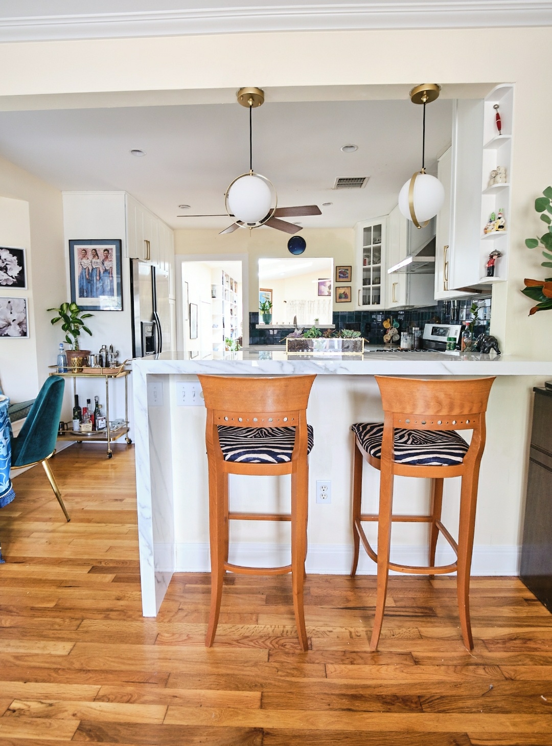 1906 Collier Street Austin, TX 78704 - Photo 7 of 40 View of the kitchen from the front sitting room. The kitchen features a kitchen breakfast bar made of porcelain countertops with side waterfall, decorative light fixtures, white cabinetry, a peninsula, and glass insert cabinets.