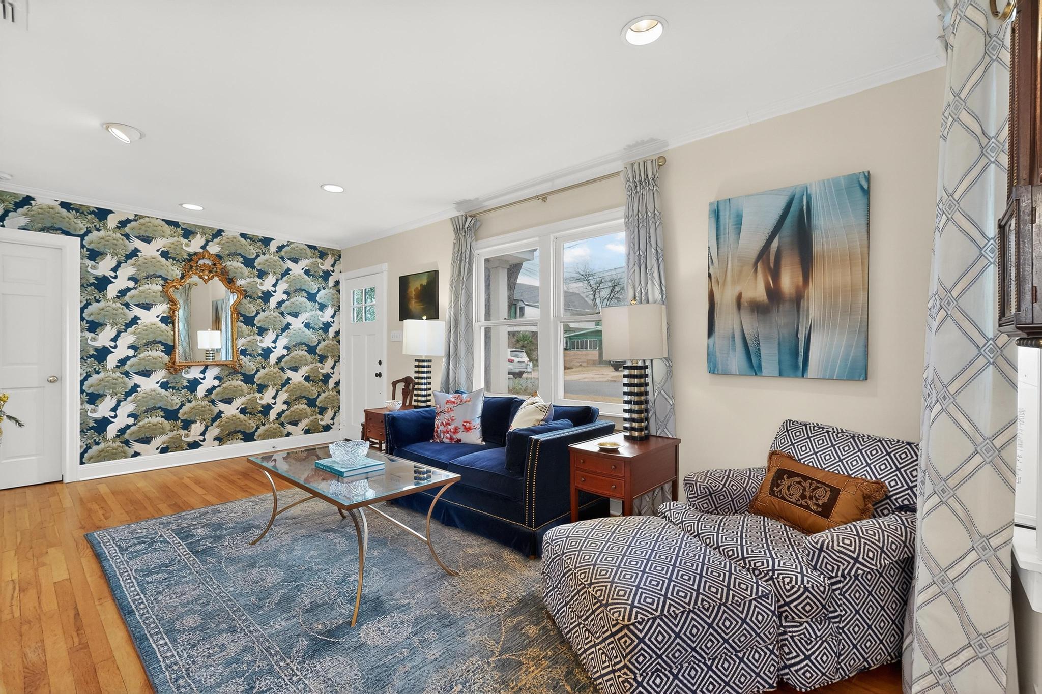 1906 Collier Street Austin, TX 78704 - Photo 9 of 40 Another view of the front living room with hardwood flooring, an accent wall of unique and bright wallpaper to elevate the space, and recessed lighting.
