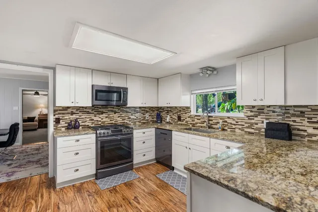 a kitchen with stainless steel appliances granite countertop a stove a sink and a microwave