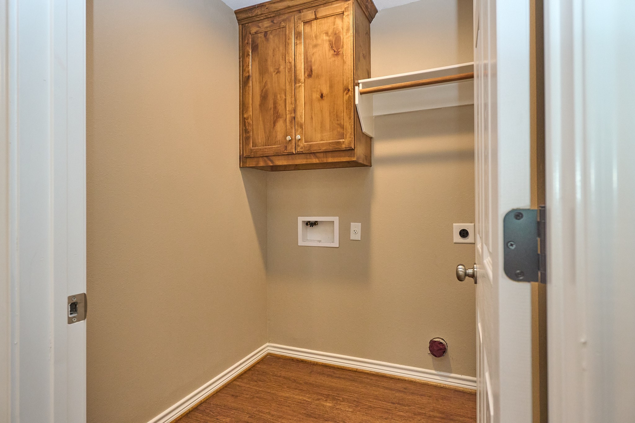 1807 Nuches Lane Bryan, TX 77803 - Photo 22 of 27 This is a compact laundry room featuring wood flooring, a wooden cabinet, and connections for a washer and dryer.